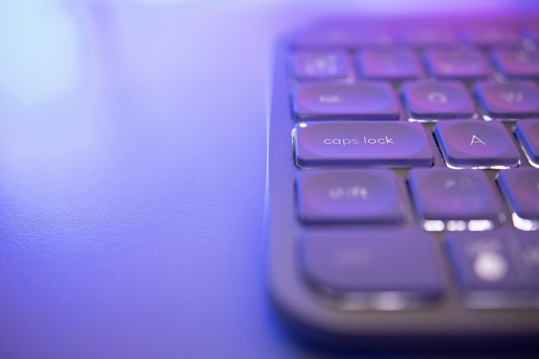 Mains tapant sur un clavier d'ordinateur portable près d'un carnet de notes